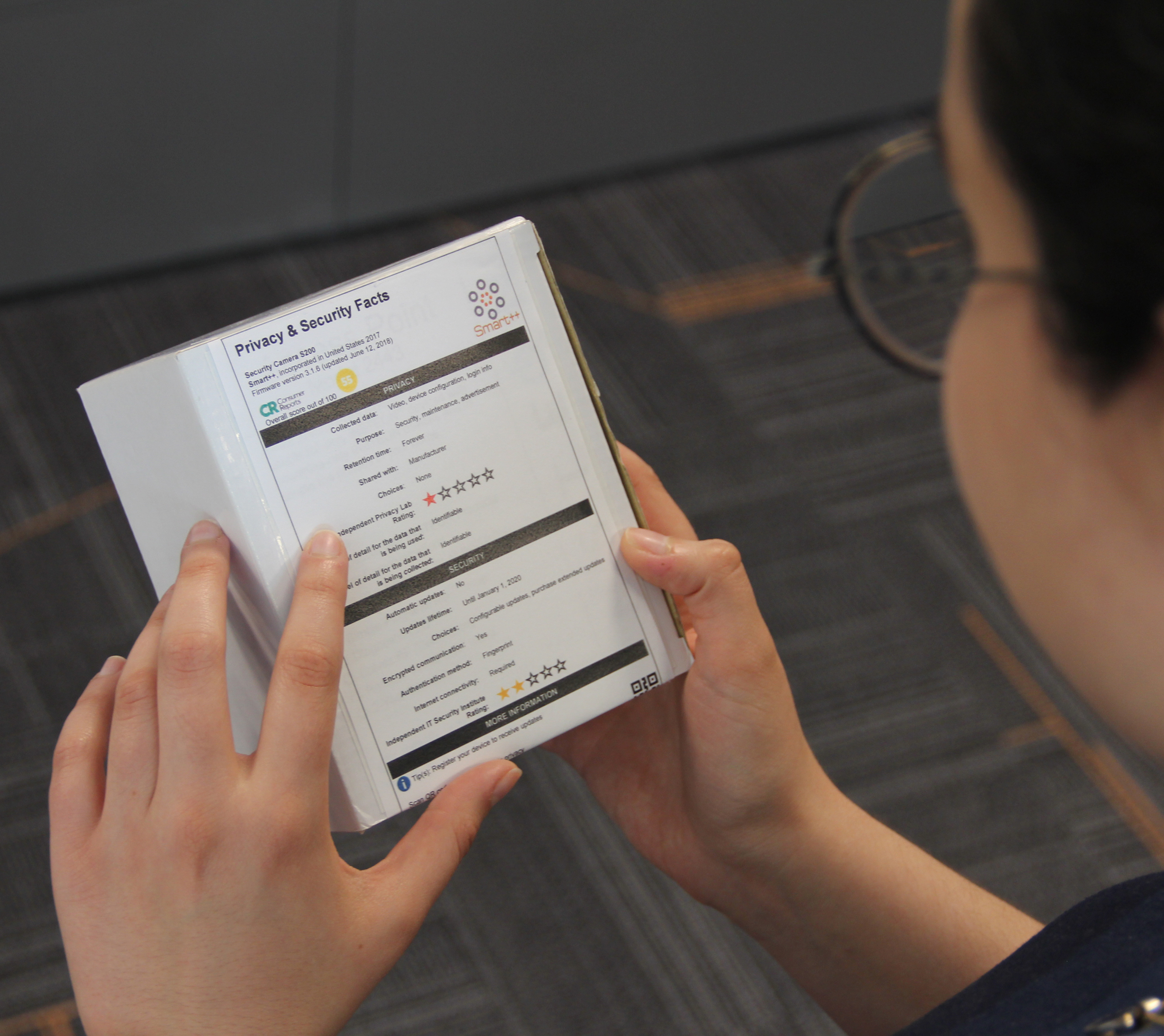 A woman (Pardis Emami-Naeini, Ph.D. student) looking at a privacy and security facts label, which looks similar to a nutritional label