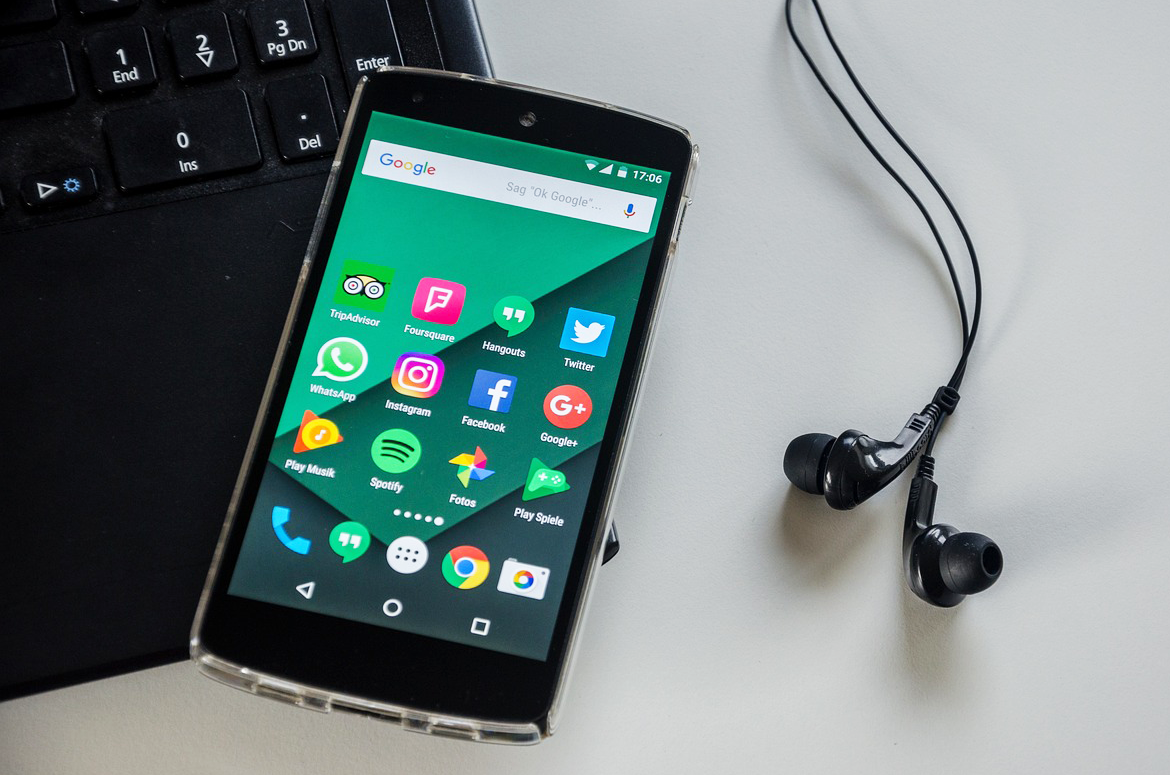 stock image of an Android phone next to a laptop and headphones