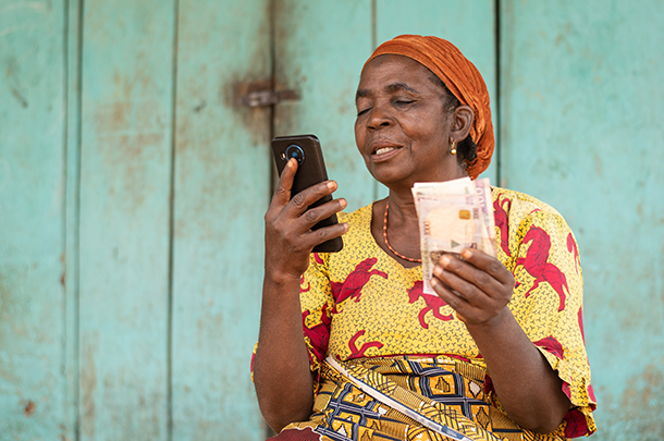 Image of a woman holding money and looking at a mobile phone