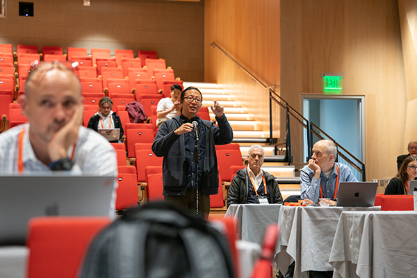 Photo of an attendee standing at a microphone asking a question to a speaker at the CyLab Partner's Conference