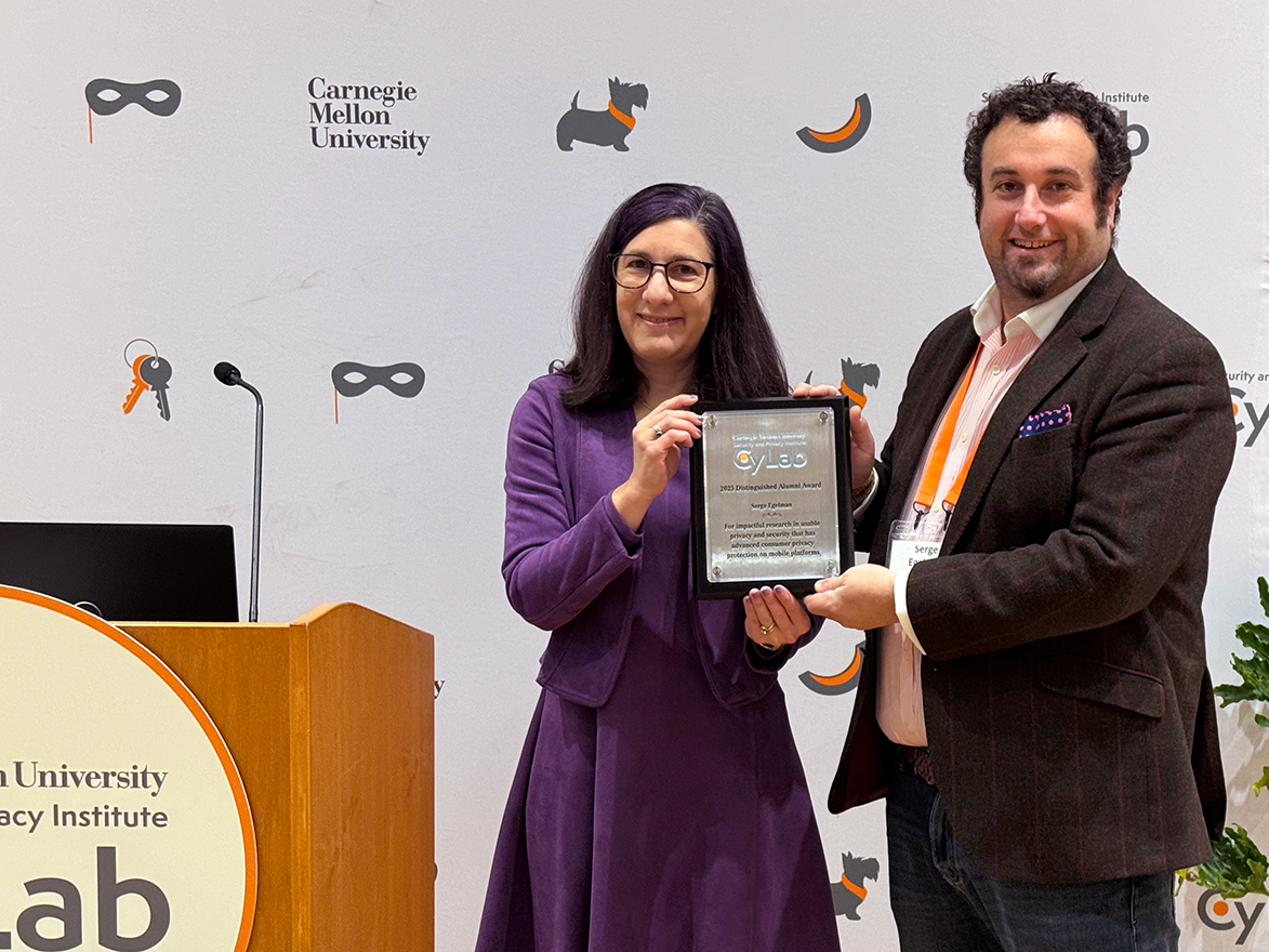 Photo of Lorrie Cranor and Serge Egelman posing with the Distinguished Alumni Award plaque at the CyLab Partners Conference