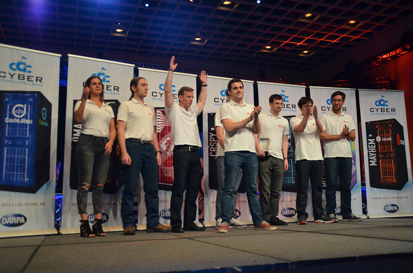photo of a group of researchers celebrating a win onstage at the 2016 DARPA Grand Challenge